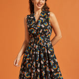 Woman wearing a sleeveless cotton summer dress with rainbow and floral pattern on an orange background