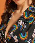 Close-up of a woman wearing a black dress with colorful rainbow and floral patterns.