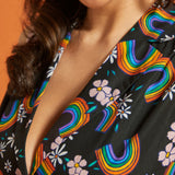 Close-up of a woman wearing a black dress with colorful rainbow and floral patterns.