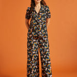 Woman wearing a rainbow floral patterned short sleeve cotton blouse with matching palazzo pants