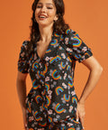 Woman wearing a button front summer blouse with rainbow and floral patterns