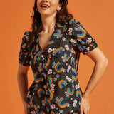 Woman wearing a button front summer blouse with rainbow and floral patterns