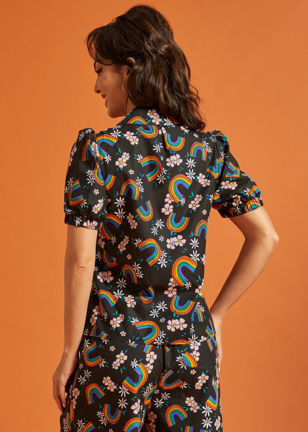 Back view of a woman wearing a black shirt and pants set with colorful rainbow and floral patterns