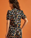 Back view of a woman wearing a black shirt and pants set with colorful rainbow and floral patterns