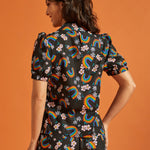 Back view of a woman wearing a black shirt and pants set with colorful rainbow and floral patterns