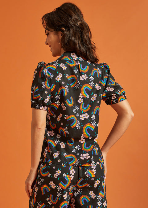 Back view of a woman wearing a black shirt and pants set with colorful rainbow and floral patterns