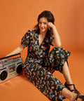 Woman in a floral rainbow print outfit sitting down with a retro boombox.