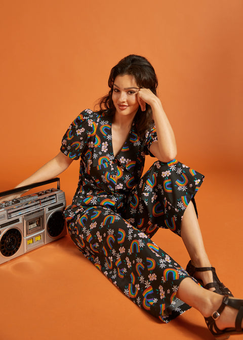 Woman in a floral rainbow print outfit sitting down with a retro boombox.
