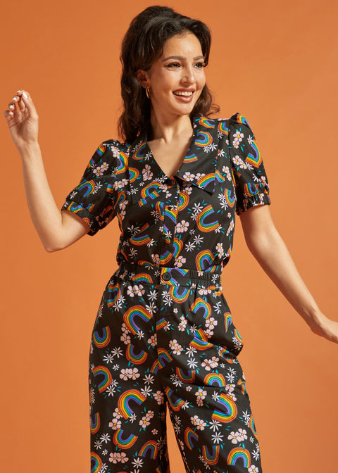 Woman wearing a black shirt and pants with colorful rainbow and floral patterns