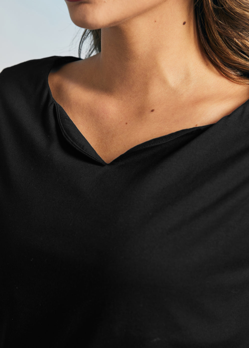 Close-up of the black boatneck neckline and smooth stretch knit fabric