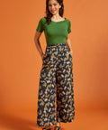 Woman wearing a vintage inspired green top and rainbow patterned wide leg pants