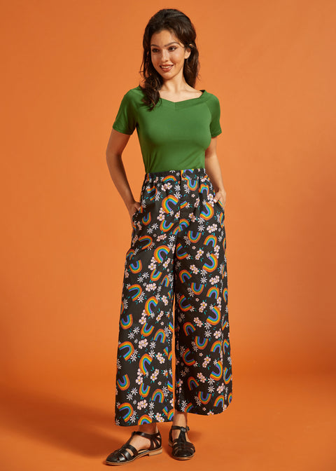 Woman wearing a vintage inspired green top and rainbow patterned wide leg pants