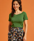 Woman wearing a green top and colorful rainbow-patterned pants on an orange background