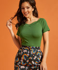 Woman wearing a green top and colorful rainbow pants on an orange background
