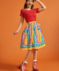 Woman wearing a red top and colorful striped skirt with roller skates on an orange background