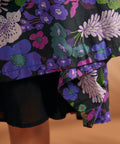 Close-up of colorful purple and green floral print on black cotton dress