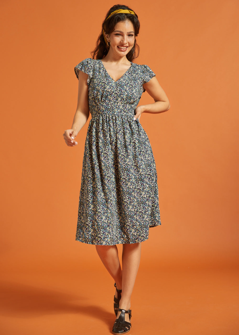 Full-length view of black floral dress with smocked waist and flutter sleeves