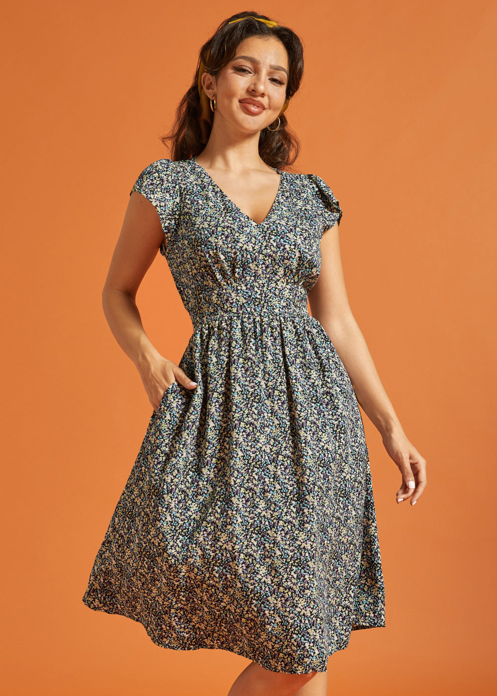 Woman wearing a black floral midi dress with V-neckline and flutter sleeves