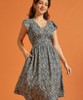 Woman wearing a black floral midi dress with V-neckline and flutter sleeves