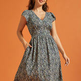 Woman wearing a black floral midi dress with V-neckline and flutter sleeves