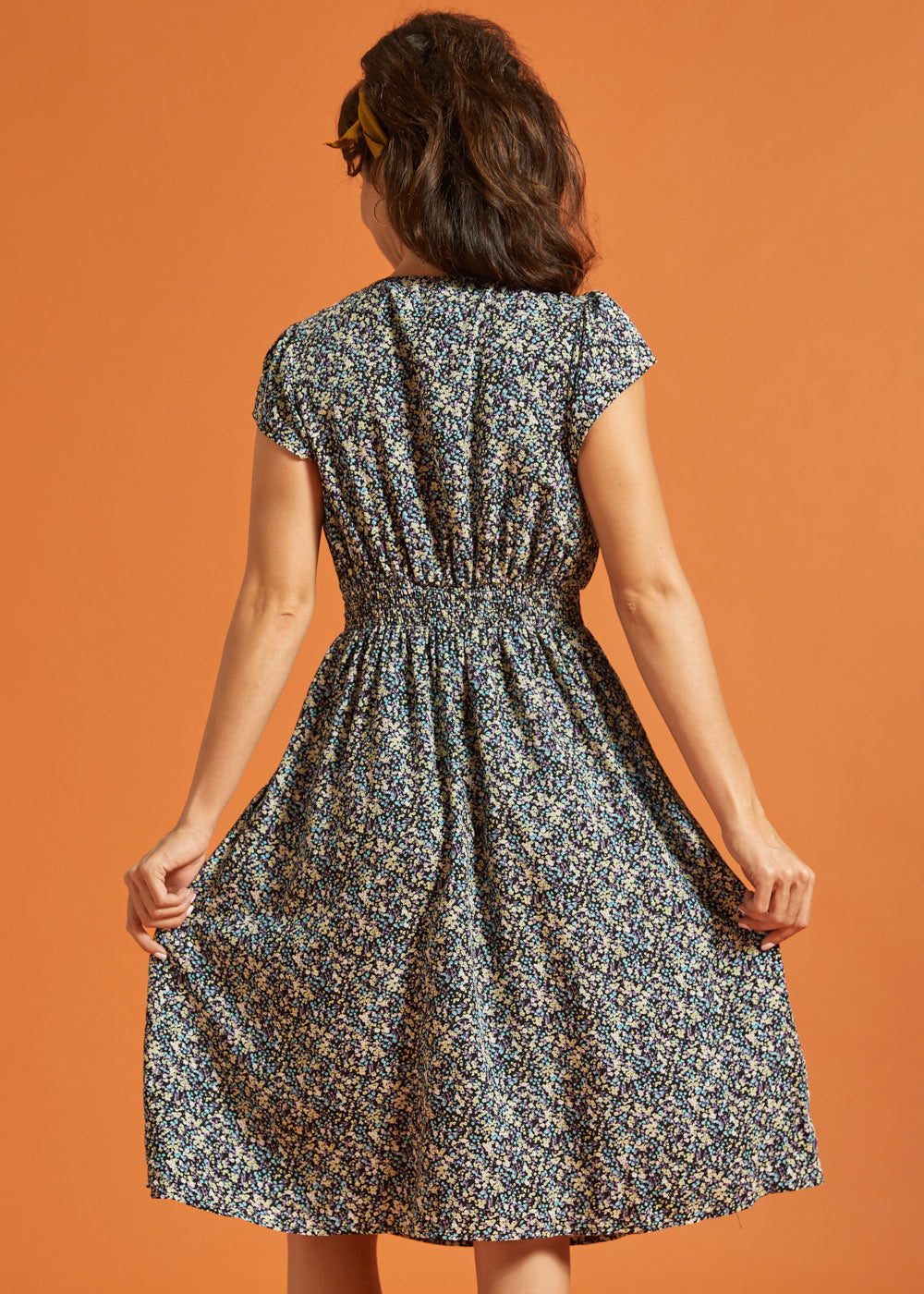 Back view of black floral fit-and-flare dress with gathered waist