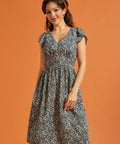 Woman wearing a black floral fit-and-flare dress with flutter sleeves and pockets