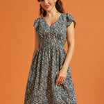Woman wearing a black floral fit-and-flare dress with flutter sleeves and pockets