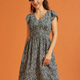 Woman wearing a black floral fit-and-flare dress with flutter sleeves and pockets