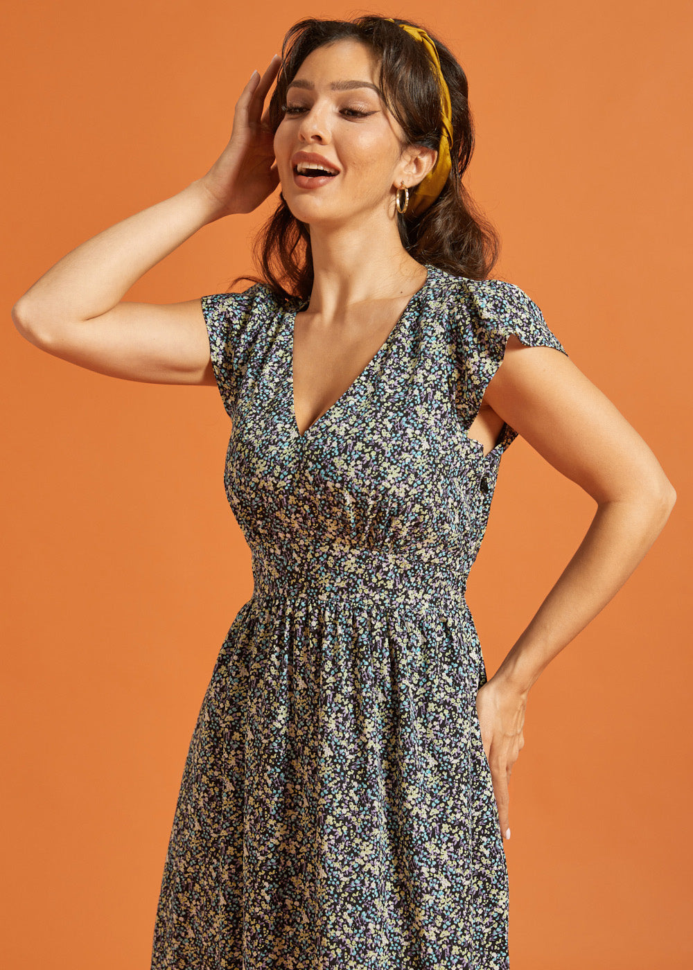 Woman wearing a floral dress with pockets and a flattering smocked waist silhouette