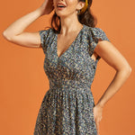 Woman wearing a floral dress with pockets and a flattering smocked waist silhouette
