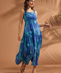 Woman wearing a blue tropical print tiered maxi dress with square neckline and open-back bow