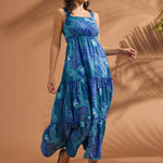Woman wearing a blue tropical print tiered maxi dress with square neckline and open-back bow