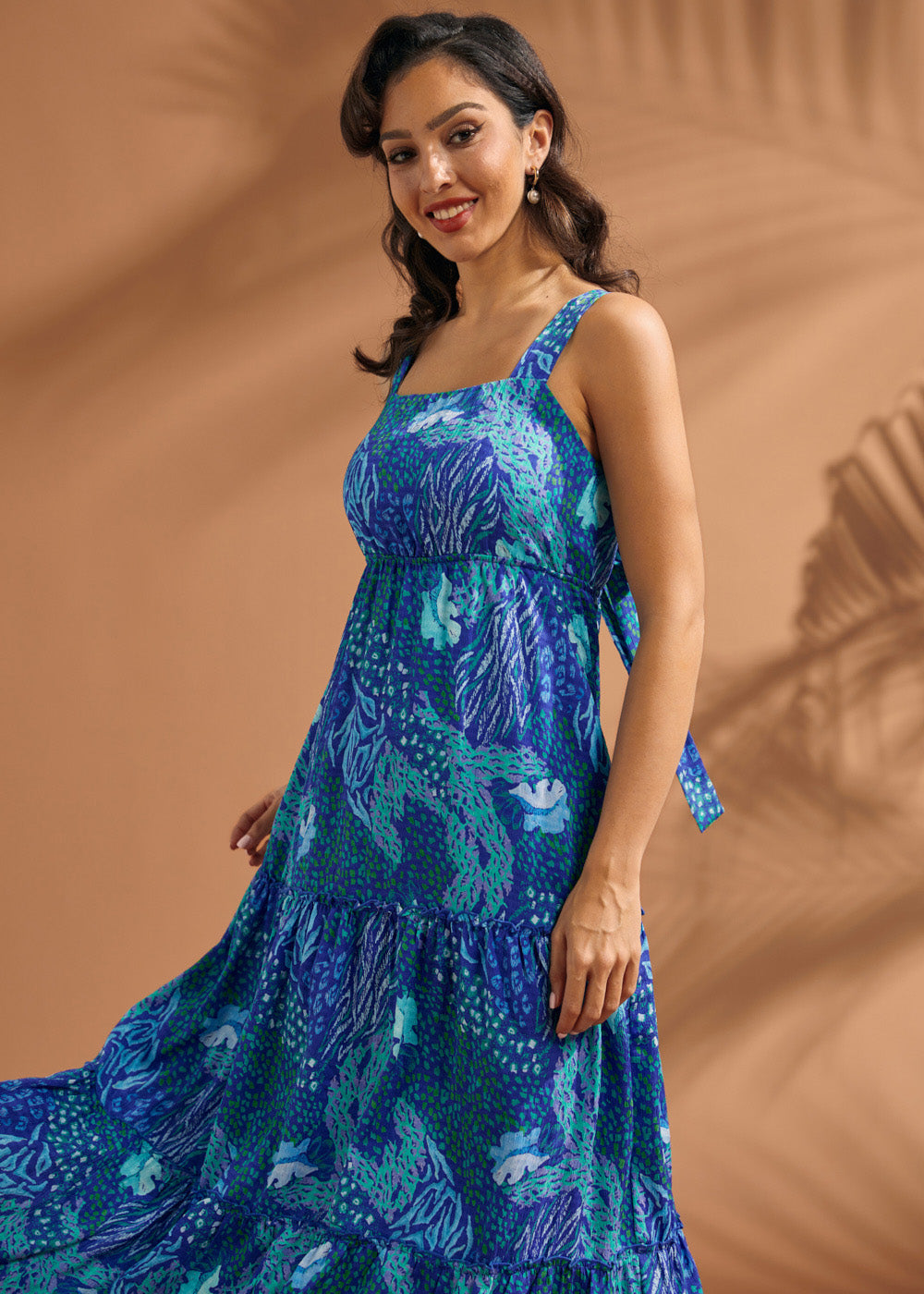 Woman wearing a breezy blue resort dress with square neckline and flowing silhouette