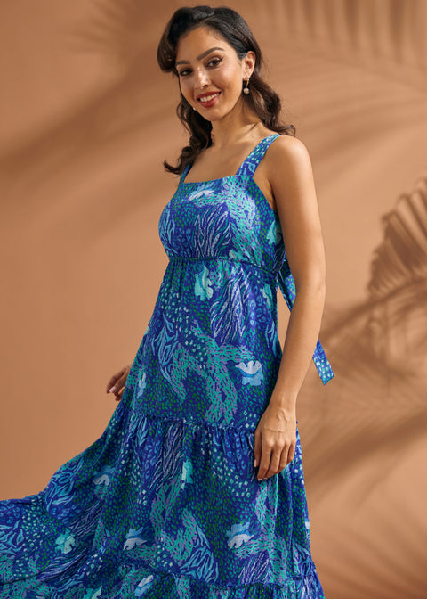 Woman wearing a breezy blue resort dress with square neckline and flowing silhouette