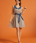 Woman wearing a vintage-inspired sleeveless fit-and-flare dress with a colorful horseshoe print, oversized blue Peter Pan collar, and matching tie belt.