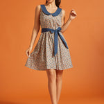 Woman wearing a vintage-inspired sleeveless fit-and-flare dress with a colorful horseshoe print, oversized blue Peter Pan collar, and matching tie belt.
