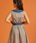 Back view of a retro-inspired sleeveless horseshoe print dress with a statement blue collar and coordinating tie belt.