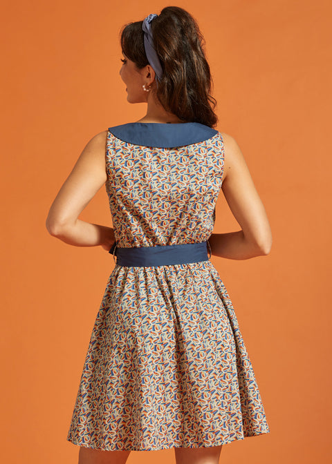 Back view of a retro-inspired sleeveless horseshoe print dress with a statement blue collar and coordinating tie belt.
