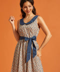 Woman wearing a vintage-style cotton dress with a lucky horseshoe print, full skirt, side pockets, and blue Peter Pan collar.