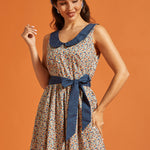 Woman wearing a vintage-style cotton dress with a lucky horseshoe print, full skirt, side pockets, and blue Peter Pan collar.