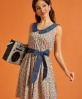 Woman carrying a boombox while wearing a retro fit-and-flare dress with a horseshoe print, oversized Peter Pan collar, and waist tie.