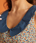 Detail of the oversized blue Peter Pan collar against a colorful horseshoe print cotton dress.