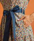 Close-up of the removable blue sash and hidden side pocket on a colorful novelty horseshoe print cotton dress.