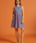 Woman modeling a sleeveless cotton shift dress with pink floral print and patch pockets.