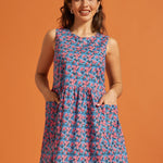 Woman wearing a vintage-inspired sleeveless floral dress with roomy front pockets.