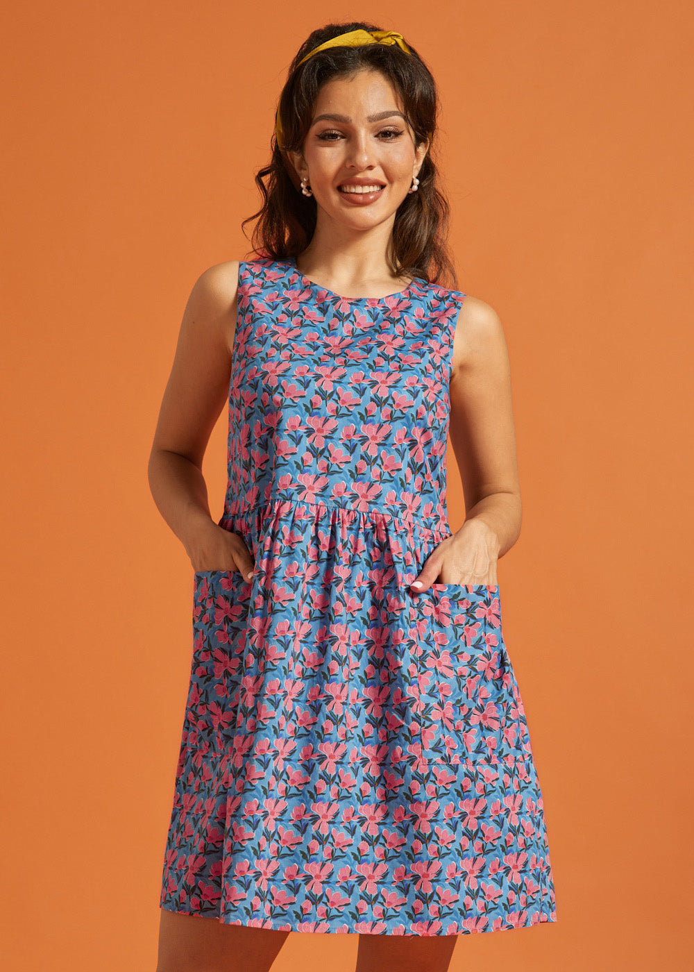 Woman wearing a vintage-inspired sleeveless floral dress with roomy front pockets.