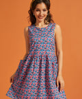 Woman wearing a sleeveless blue and pink floral A-line dress with oversized patch pockets.