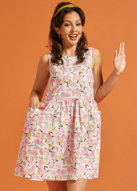 Woman wearing a pink citrus print sleeveless swing dress with oversized pockets