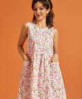 Woman wearing a sleeveless pink citrus print dress with patch pockets