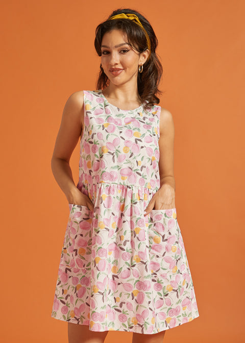 Woman wearing a sleeveless pink citrus print dress with patch pockets